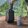 Fitting the TAHAN dispenser onto a water container at a riverside campsite